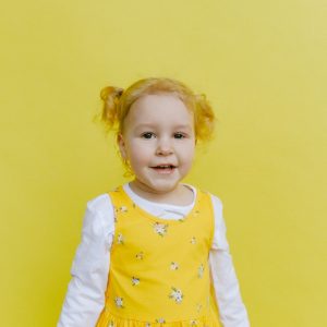Adorable Girl Standing Beside Yellow Wall