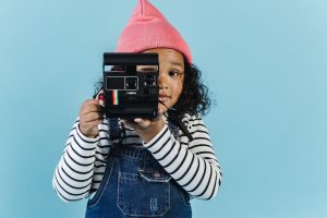 Sweet black girl taking pictures on film camera